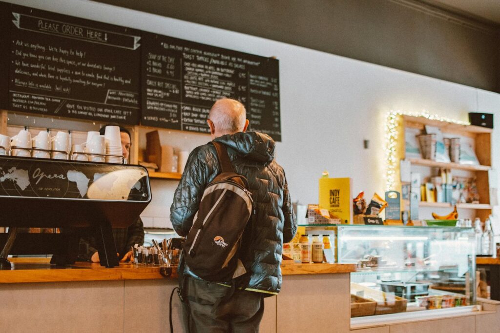 A casual café setting with a customer ordering coffee at the counter.